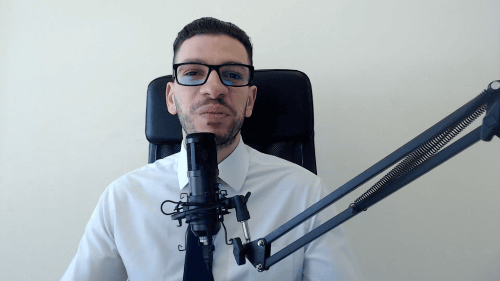 Man speaking at AIIT conference with microphone and headset.