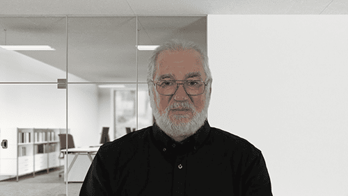 Senior man with white hair and beard in a professional office environment.