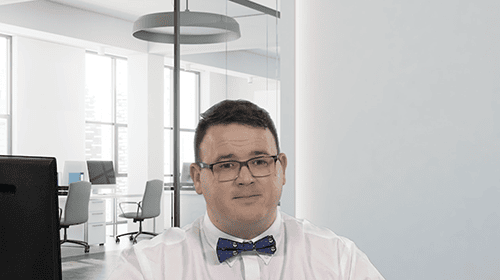 Business professional in modern office with glasses and bow tie.